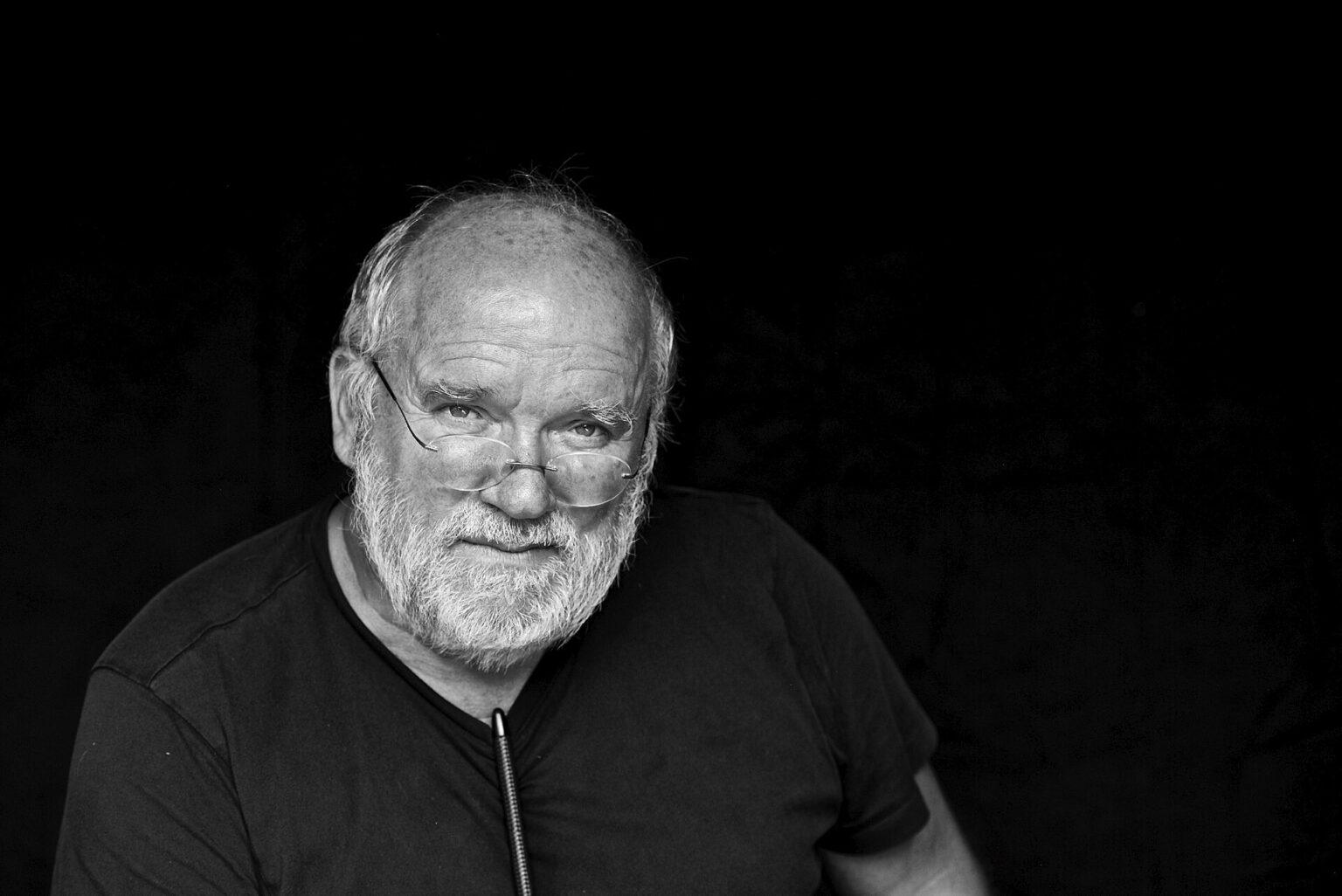 Schwarz-Weiß-Portrait des Fotografen Peter Lindbergh vor schwarzem Hintergrund