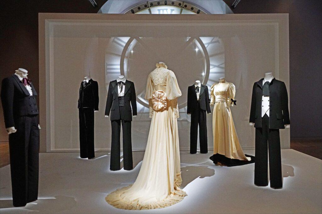 Schwarze Smoking-Anzüge und helle Abendkleider von Yves Saint Laurent auf Schaufensterpuppen in einer Ausstellung im Musée d’Orsay
